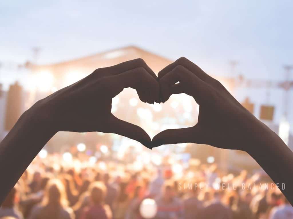 Hands forming a heart at an evening concert during a family night out.