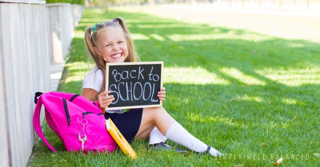 Young girl holding up back to school chalkboard sign for a photo. 