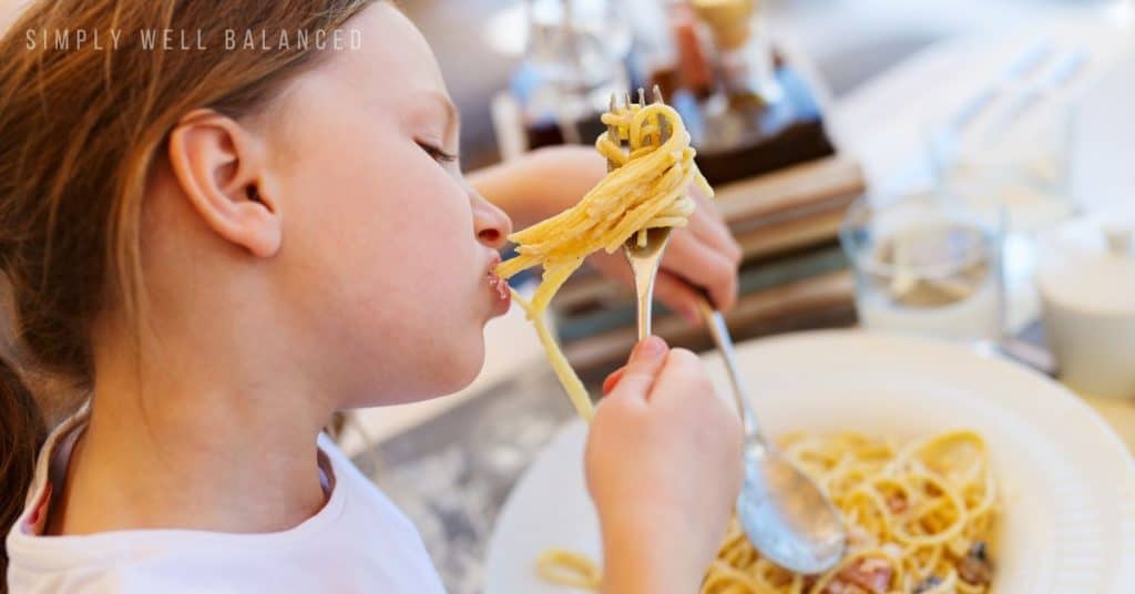 A girl eating spaghetti for National Spaghetti Day - Fun January Holidays.