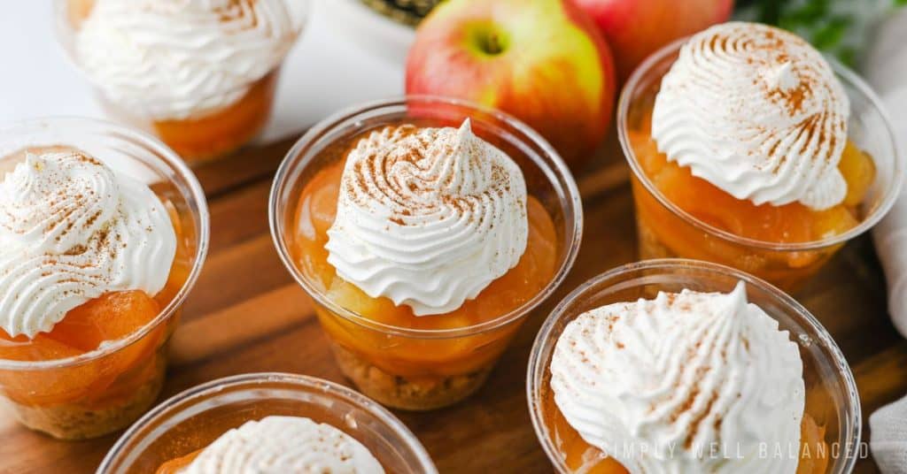6 individual No Bake Apple Pie dessert cups on a wooden serving board.